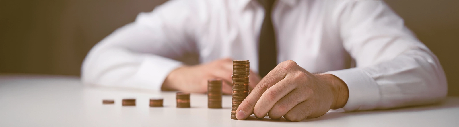 Article cover image depicting a man arranging coins in stacks.