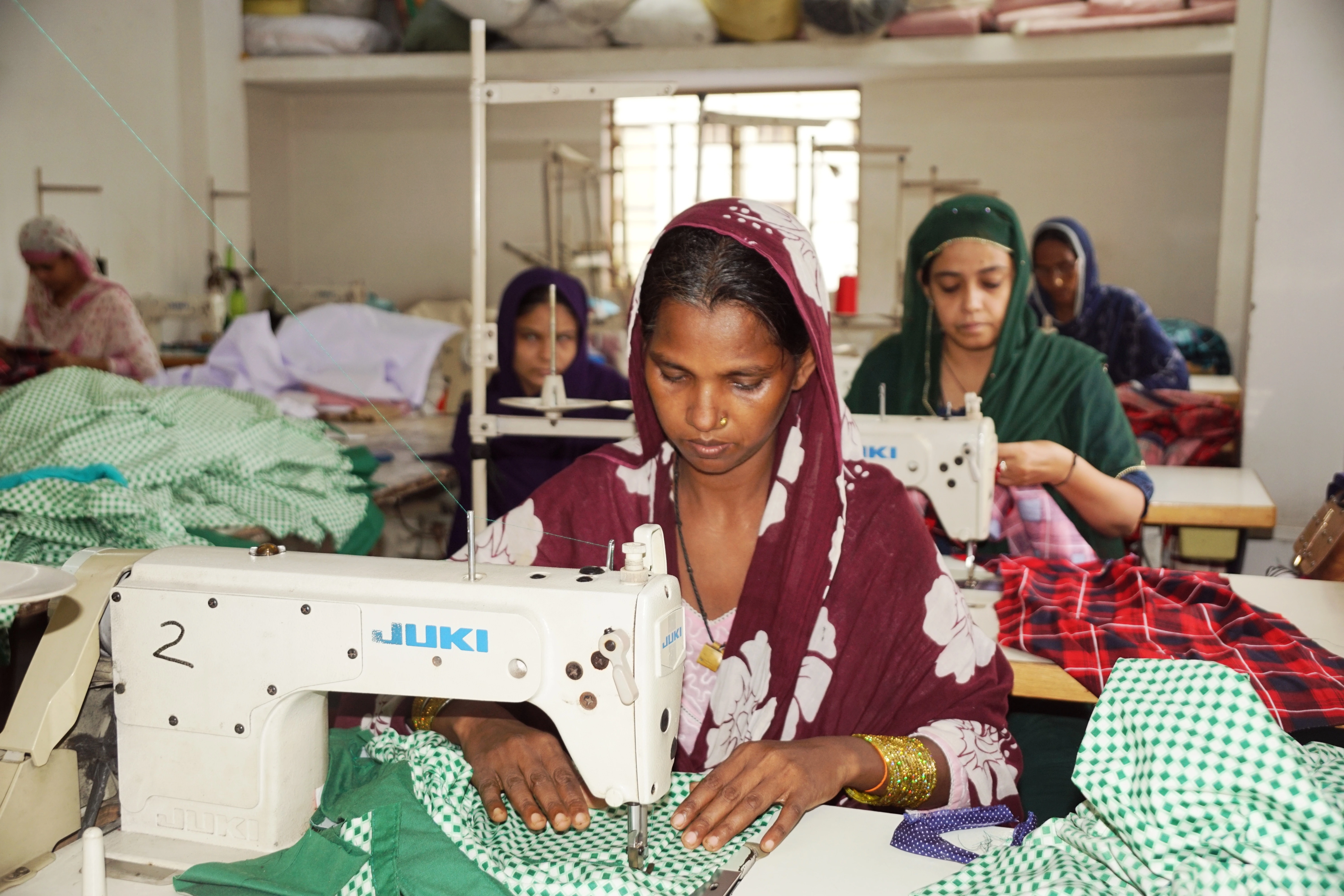 Underprivileged women sewing with sewing machines.